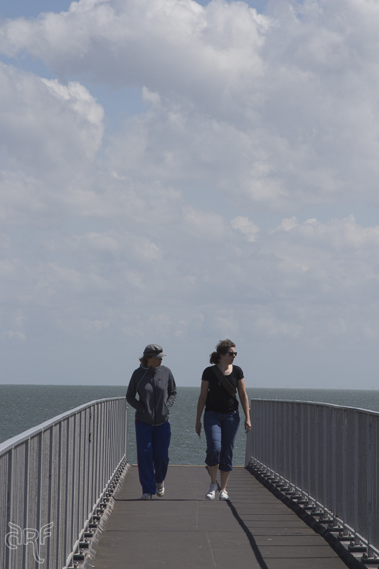 two girls walking on bridge which crosses the road overhead