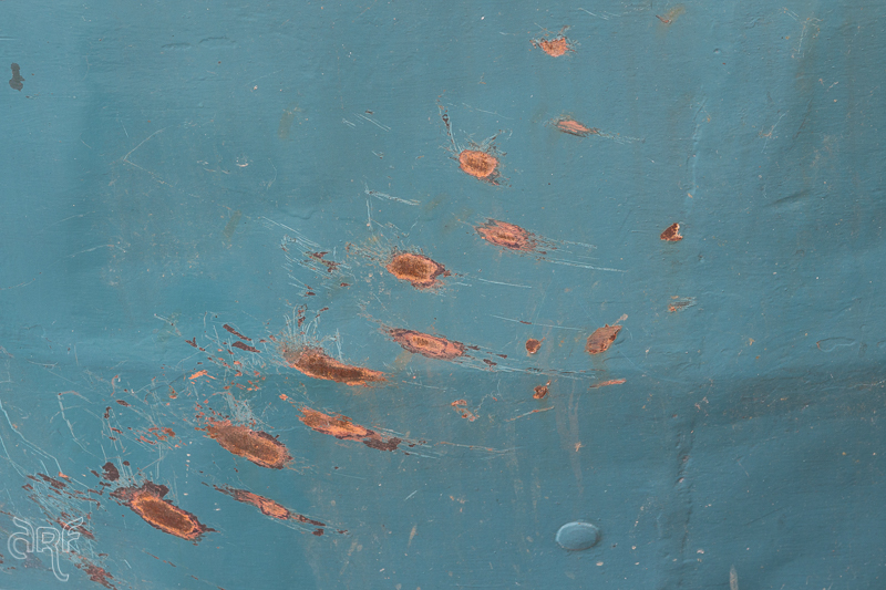 red rust on turquoise ship hull