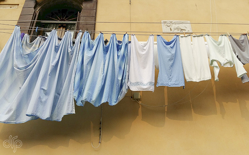 blue and white laundry at Naples yellow colored house in Venice, Italy