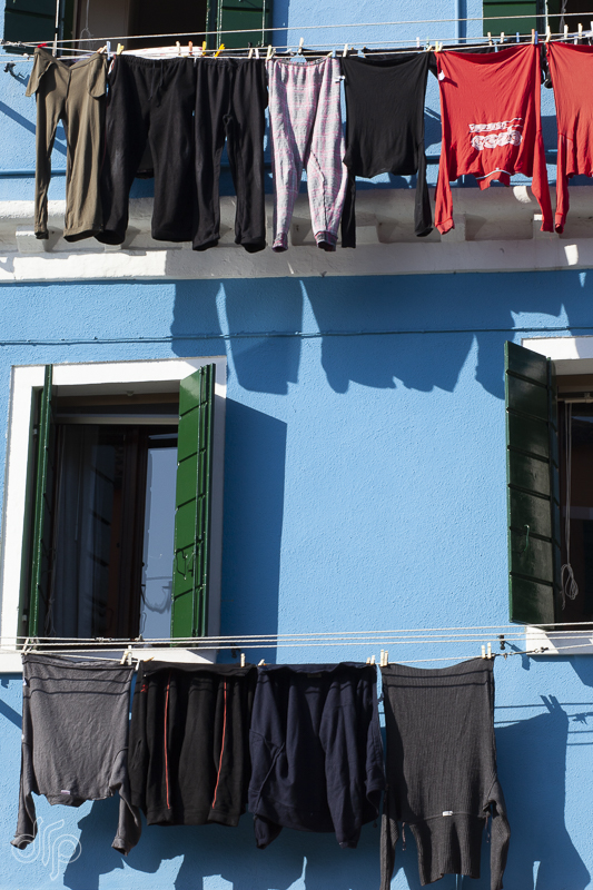 two rows of laundry at blue house in Burano, Italy