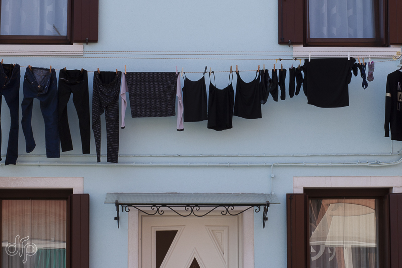 black laundry at a blue house in Burano, Italy