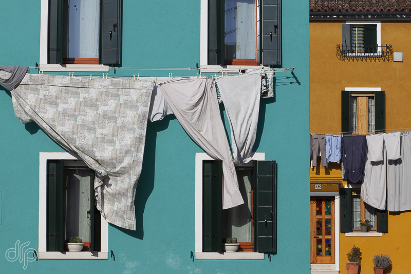 laundry at green and ochre colored houses in Burano, Italy