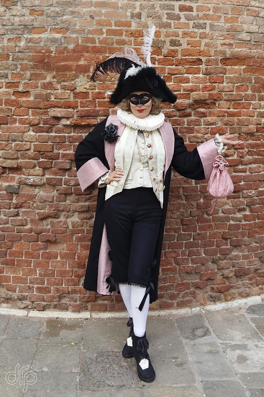 The character of Lélio posing in front of a rounded wall in Venice, Italy