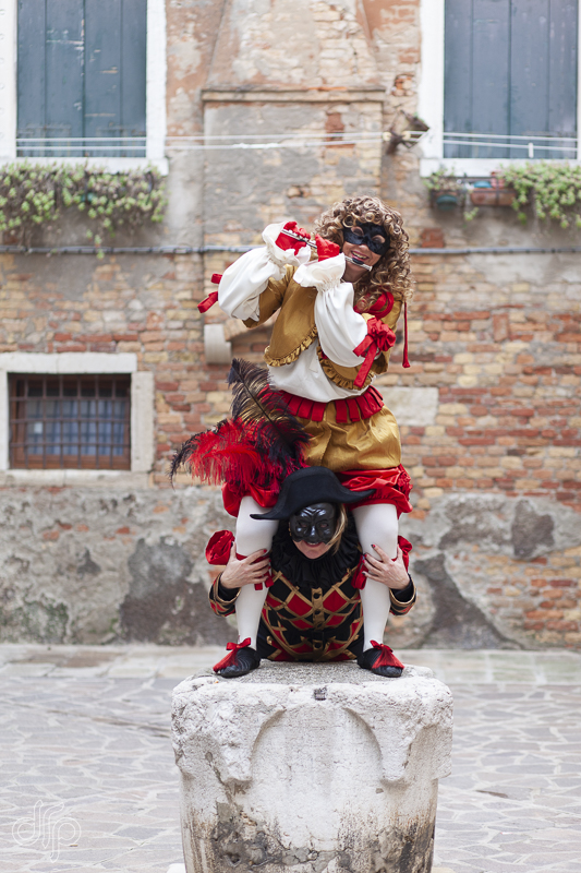 The characters of Arlecchina and Ottavio from the Commedia dell'Arte on top of a water well in Venice, Italy