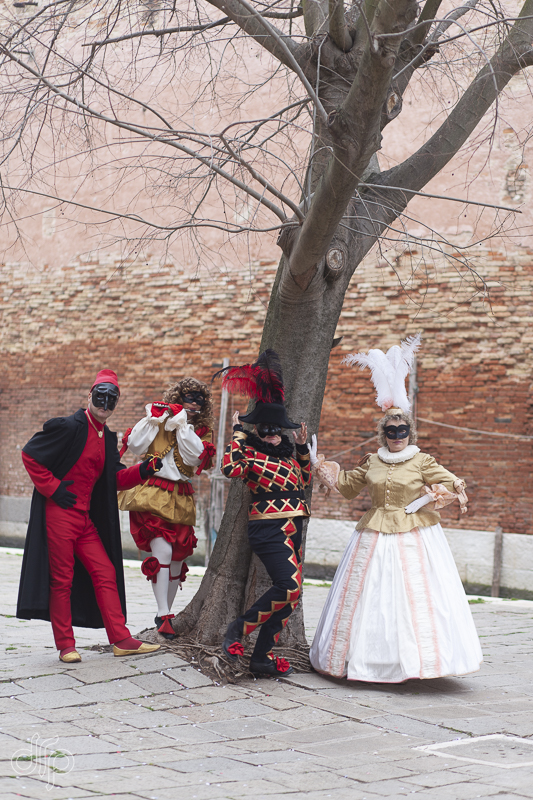 Four characters of Commedia dell'Arte posing around a tree in Venice, Italy
