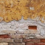Indian Yellow Hue and rusty colored textured wall with bricks n Venice, Italy