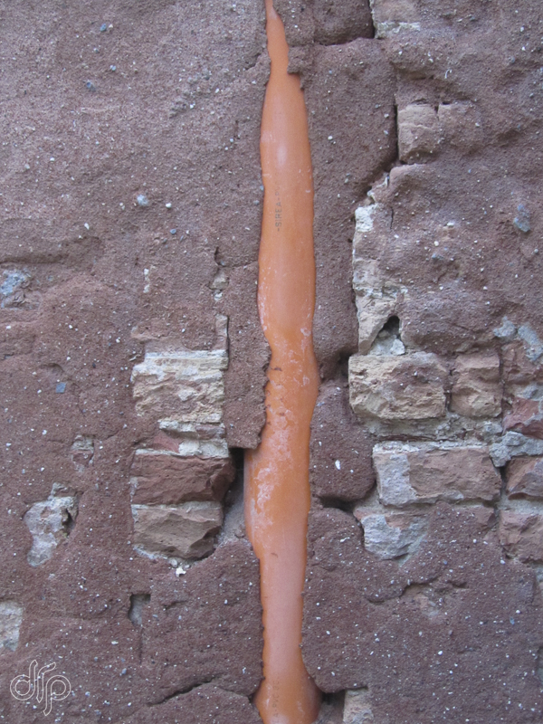 Orange downspout in a brick wall in Venice, Italy