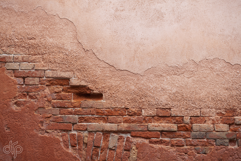 Salmon colored textured wall with bricks in Venice, Italy