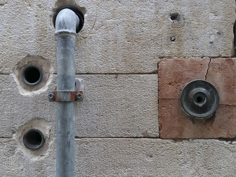 Wall abstract with downspout, doorbell and three holes in Venice, Italy