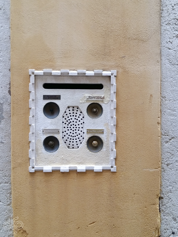 Yellow wall abstract with four doorbells in Venice, Italy
